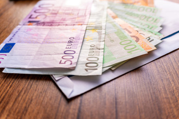 Euro banknotes in salary envelope. Open envelope with money banknotes on table. White envelope with Euro bills. Closeup on Envelope full of euro cash. Euro money currency. International monetary