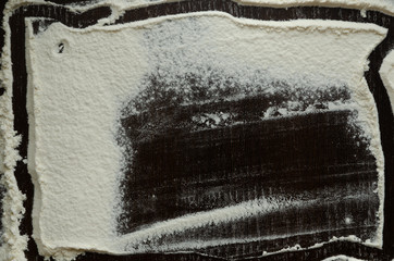 Texture of white flour on a dark wooden background in the form of a frame.
