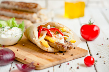 Wrap kebab with ingredients on wood table.