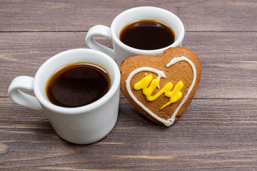 Two cups of coffee and heart cookies on a wooden table on Valentine's Day