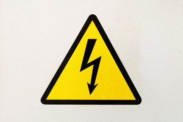 Generic high voltage danger sign, symbol. Sign of danger high voltage symbol on the white wall. Warning icon