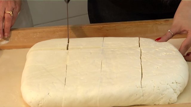 Close-up of Halloumi Cyprus cheese as a cheesemaker slices it into smaller pieces