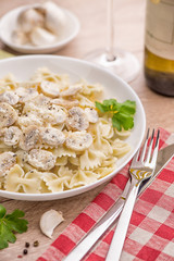 Spaghetti with champignons and parsley on a light wood table.