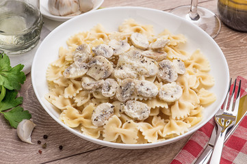 Spaghetti with champignons and parsley on a light wood table.