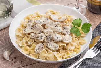 Spaghetti with champignons and parsley on a light wood table.