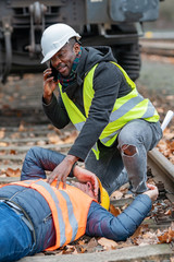 Railroad engineer injured in an accident at work on the railway tracks. Calling for help - obrazy, fototapety, plakaty