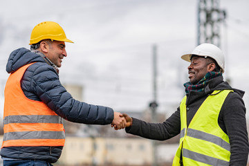 Successful handshake deal: multi-ethnic engineers reaching an agreement on construction site