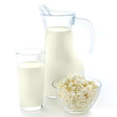 Transparent glass and a jug of useful fresh milk along with a plate of cottage cheese on a clean white background.