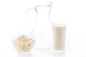 Fresh milk in a glass poured from a jug with a bowl of cottage cheese. Dairy products in the morning for breakfast are very healthy.