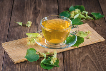 Lime green tea. Cup with fragrant lime tea, standing on a wooden table, in the rays of sunlight.
