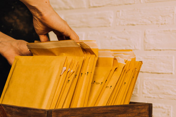 Mailings.Parcels in envelopes.Packaging for letters.Delivery orders.Stack of envelopes.Search of orders.Letters in box.Man is looking for letter.Men's hands are searching for envelope
