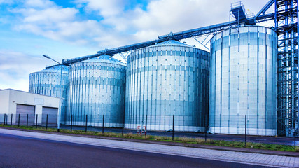Fototapeta na wymiar Agricultural silos . Storage tanks for petroleum products . Equipment refinery . White tanks for petrol and oil in tank farm with blue sky . Tank farm . 