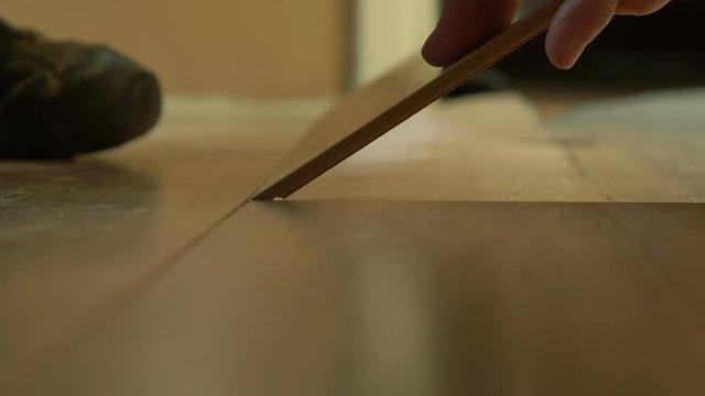 A workman installing laminate flooring in a house
