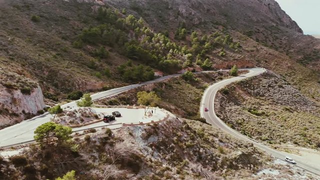 Aerial view of car driving on country road in forest. Cinematic drone shot flying over road in pine tree forest in Spain