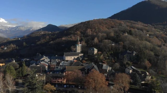 Drone shot over looking the medieval city of Conflans, in the French Alps , focus on the church of the village, in the middle of the mountains, on a sunny day. Drone is turning around the church