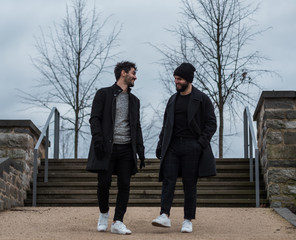 two young guys friends with beards walking in a park and having a nice conversation together