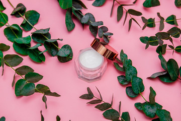 cream for skin care in the bank lies on the pink table