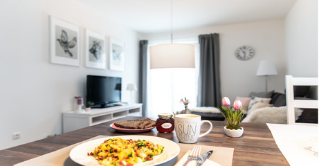 Am Morgen gedeckter Frühstückstisch mit frischen Rüheiern, Schinken und Kaffee in der Küche zubereitet