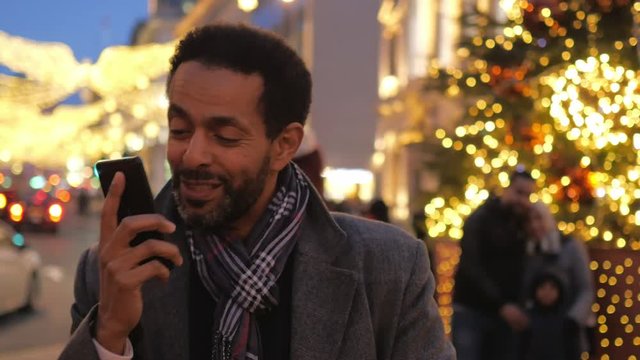Man takes a phone call in the Christmas decorated city of London