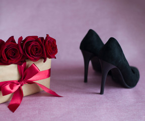 black velvet womens shoes, box tied with red ribbon, three red roses on pink background