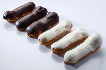 French dessert Eclair with black and white chocolate on white background. Closeup. Selective focus. High key.