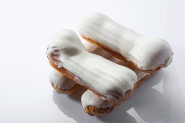 French dessert Eclair with white  chocolate on white background. Closeup. Selective focus. High key.