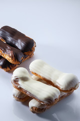 French dessert Eclair with white and black chocolate on white background. Closeup. Selective focus. High key.