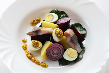 Salad from salty herring, beet, boiled potatoes, quail eggs and onions. With french mustard. High...