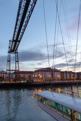 The suspension bridge is the Biscay Bridge, a World Heritage Site, with a boat crossing the estuary of Bilbao (Pays Basque, Spain)