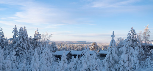 The Lapland winter landscape with wooden houses.  On the horizon a forest and a mountain. Morning and sunrise Finland Ruka.