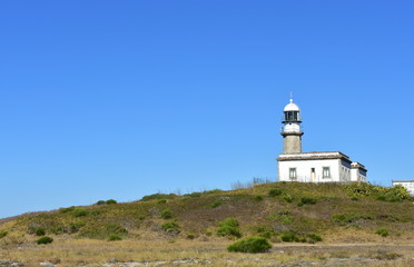 Fototapeta na wymiar Old abandoned lighthouse on a hill with blue sky. Faro de Lariño, Carnota, Coruña Province, Spain.