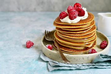 Stack of homemade delicious hot pancakes with honey, cream and raspberry.