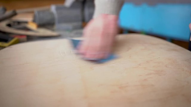 A man polishes a wooden table with scratch paper