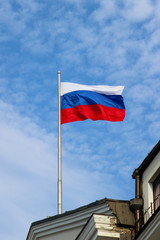 Flag of the Russian Federation streaming in the wind against the blue sky