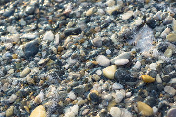pebble stones on the sea beach, the rolling waves of the sea with foam