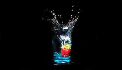Strawberries fall in a glass of water