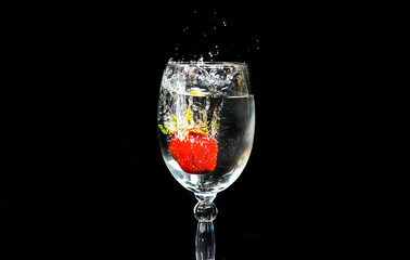 Strawberries fall in a glass of water