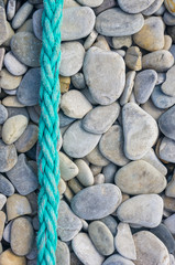old worn battered marine rope on the pebble beach on a Sunny summer day