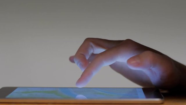 Close-up male hand looking digital map making gesture approximation touching screen of tablet