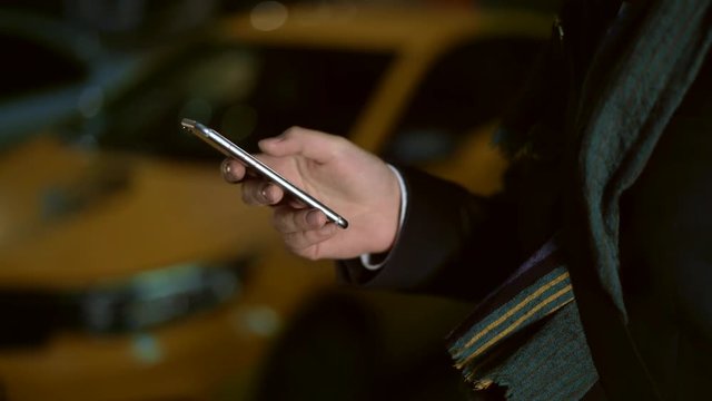 Close up shot of male hand with a phone. Taxi on the bakcground