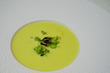Green cream of edamame bisque in a white soup plate