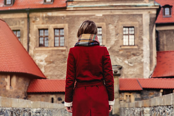 Fototapeta na wymiar Beautiful woman in red coat stay near castle in winter time. Poland