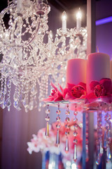 High end wedding tablescape with pillar candles and pink orchids and chandelier