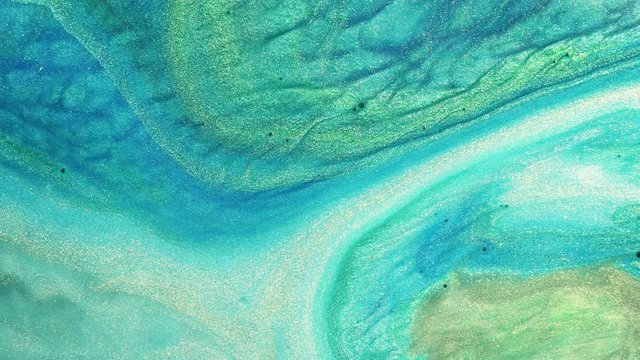 Colorful sparkling paints mix in beautiful patterns. Oil ink of blue, turqoise, green and other colors spread on the surface and mix one into another creating amazing textures and design.