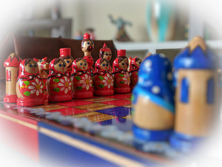A zoomed in shot on a Russian handmade red and blue chess set, made in Matryoshka (nesting doll)...