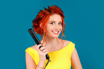 Pretty happy smiling woman holding styling straightener hair iron