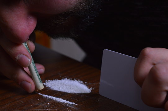 Person with a dollar bill snorting cocaine