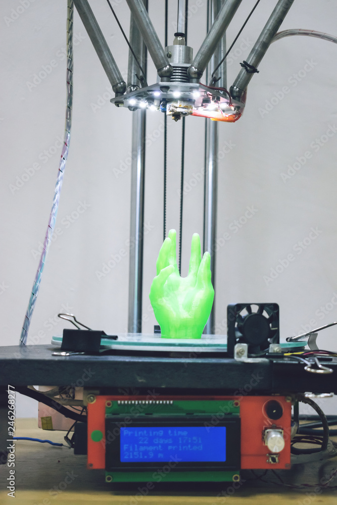 Poster green plastic 3d printed human hand stands in three-dimensional printer. object model printed on aut