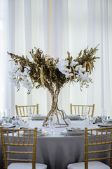 Wedding banquet. Luxury and elegant wedding reception table arrangement in gold colors, with floral composition in the centre of the table