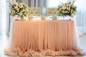 Wedding banquet. Table for newlyweds decorated with bouquets of different pastel flowers and candles.